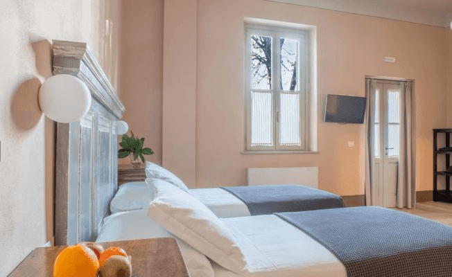 Cozy bedroom with two single beds, soft lighting, and a window overlooking trees.